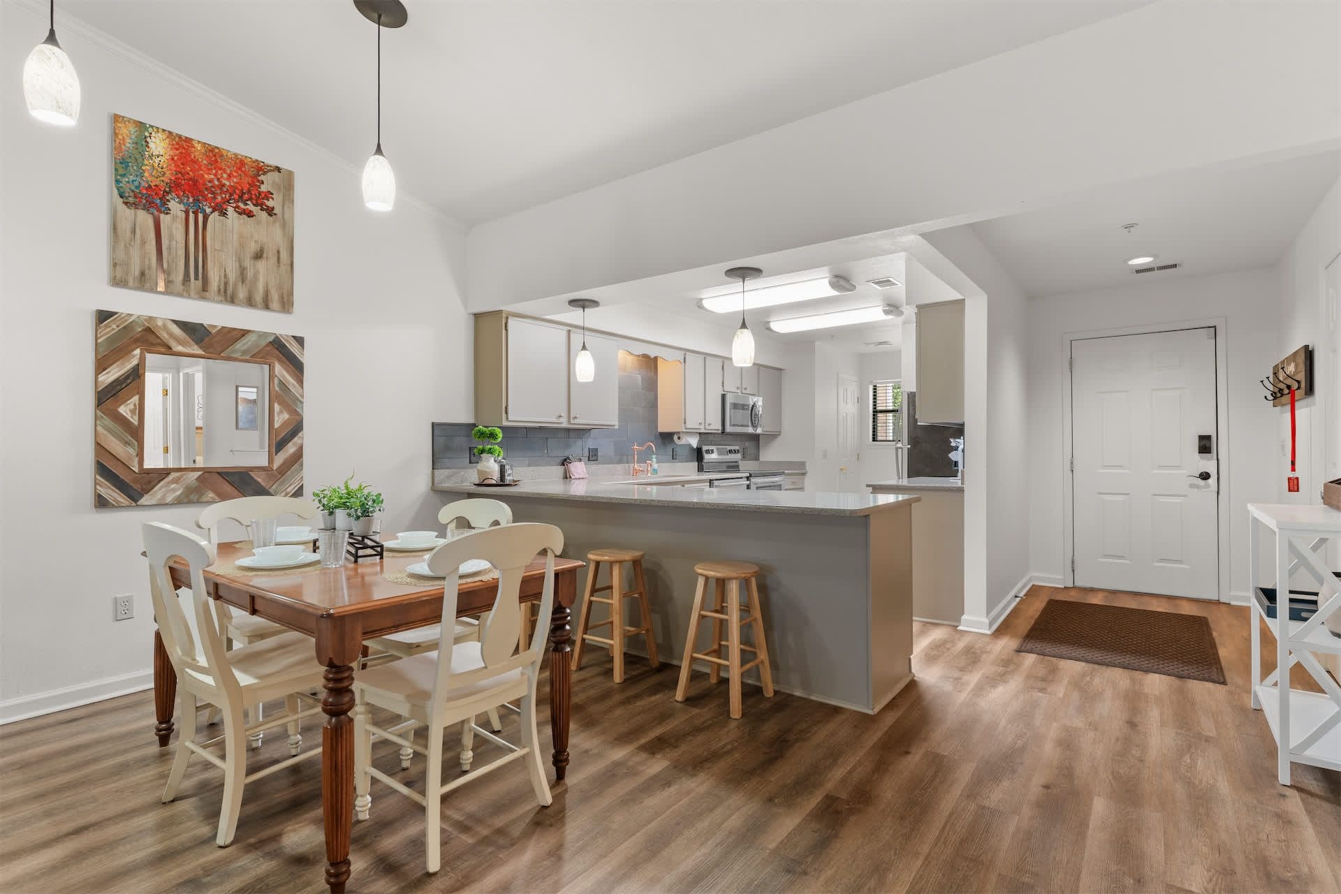 Una cocina moderna con una isla central, armarios blancos e iluminación colgante.
