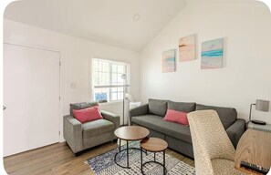 A modern living room with a grey sofa, a patterned rug, and a small round table. - Cozy 1-bedroom bungalow in Venice Hot Tub + short walk to the beach! (Los Angeles)