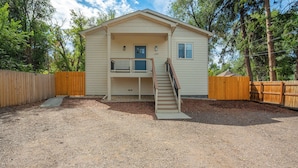 A two-story house with a front porch and a staircase leading to the upper level. - Golden Grove! Large Yard w/ Hot Tub Near Downtown (Colorado Springs)