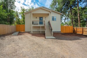 A two-story house with a front porch and a staircase leading to the upper level. - Golden Grove! Large Yard w/ Hot Tub Near Downtown (Colorado Springs)