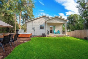 A single-story house with a covered patio area, a hot tub, and a fenced backyard. - Golden Grove! Large Yard w/ Hot Tub Near Downtown (Colorado Springs)