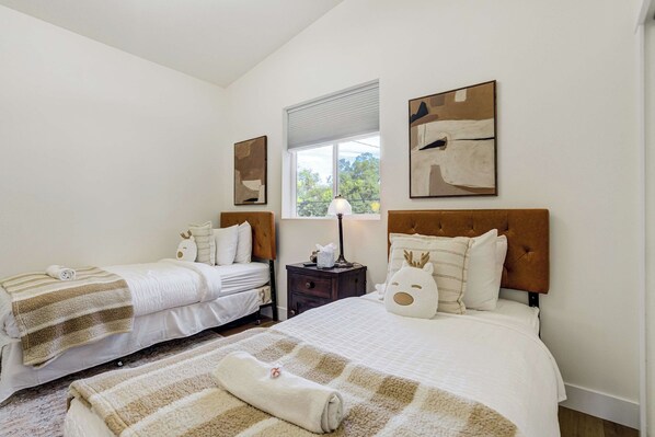 A hotel room with two beds, a window with a view, and artwork on the walls.