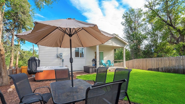 A backyard with a patio table and chairs, a barbecue grill, and a covered seating area. - Golden Grove! Large Yard w/ Hot Tub Near Downtown (Colorado Springs)