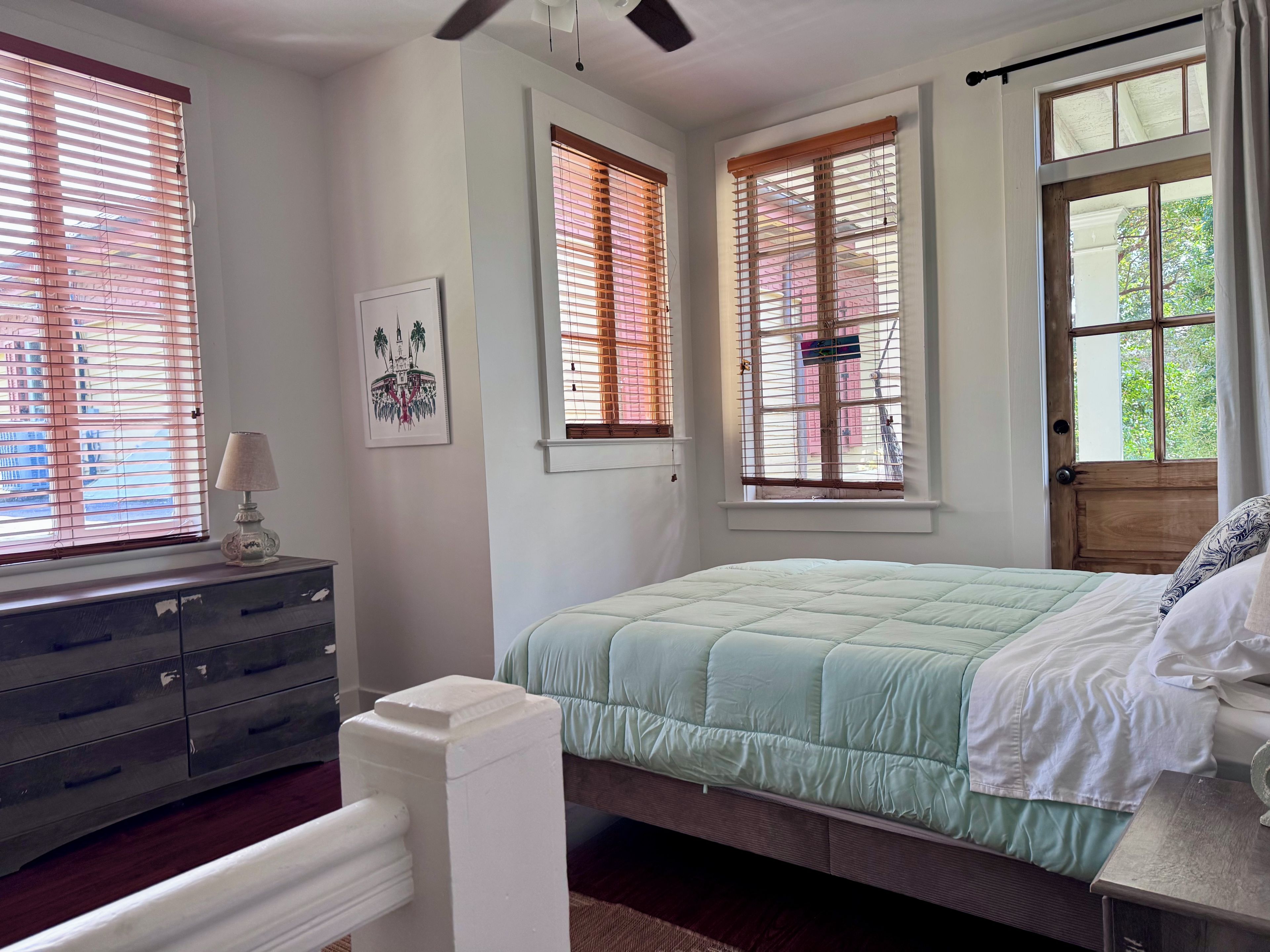 Une chambre à coucher avec un lit, une commode et des fenêtres équipées de stores.
