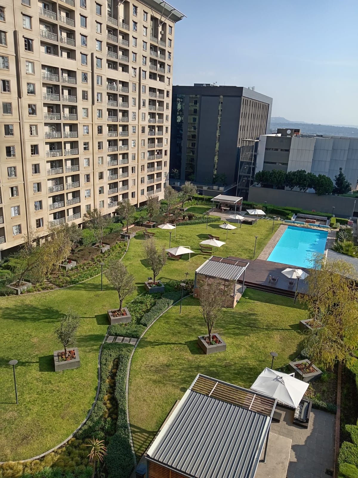 A residential building with a swimming pool, garden, and outdoor seating area.