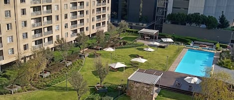 A residential building with a swimming pool, garden, and outdoor seating area.