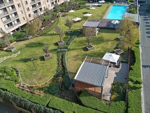 A residential complex with a swimming pool, green lawns, and a small building with a sloped roof. - Sandton Westpoint Luxury Apartments 191 (Sandton)