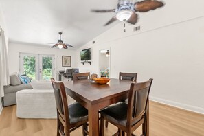 A dining area with a wooden table, four chairs, and a ceiling fan. - Cozy 2BR Condo Near Beach & Ponce Inlet (Port Orange)