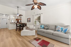 A modern living room with a grey sofa, a white armchair, and a wooden floor. - Cozy 2BR Condo Near Beach & Ponce Inlet (Port Orange)