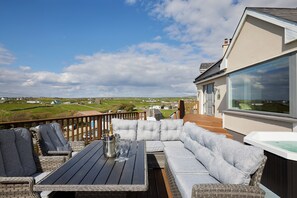 Eine Terrasse mit Sitzgelegenheit, einem Whirlpool und einem schönen Ausblick auf die Landschaft.