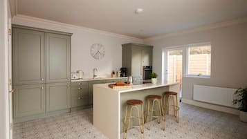 A kitchen with a central island, bar stools, a clock, and a window with a view.