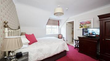 A bedroom with a bed, a TV, a dresser, and a window.