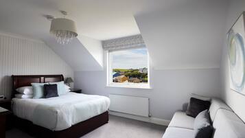 A bedroom with a large bed, a nightstand, a window with a view, a radiator, and a ceiling light fixture.
