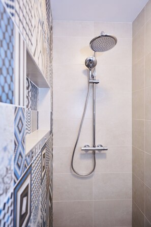Een douche met een handdouche en een kraan aan de muur.