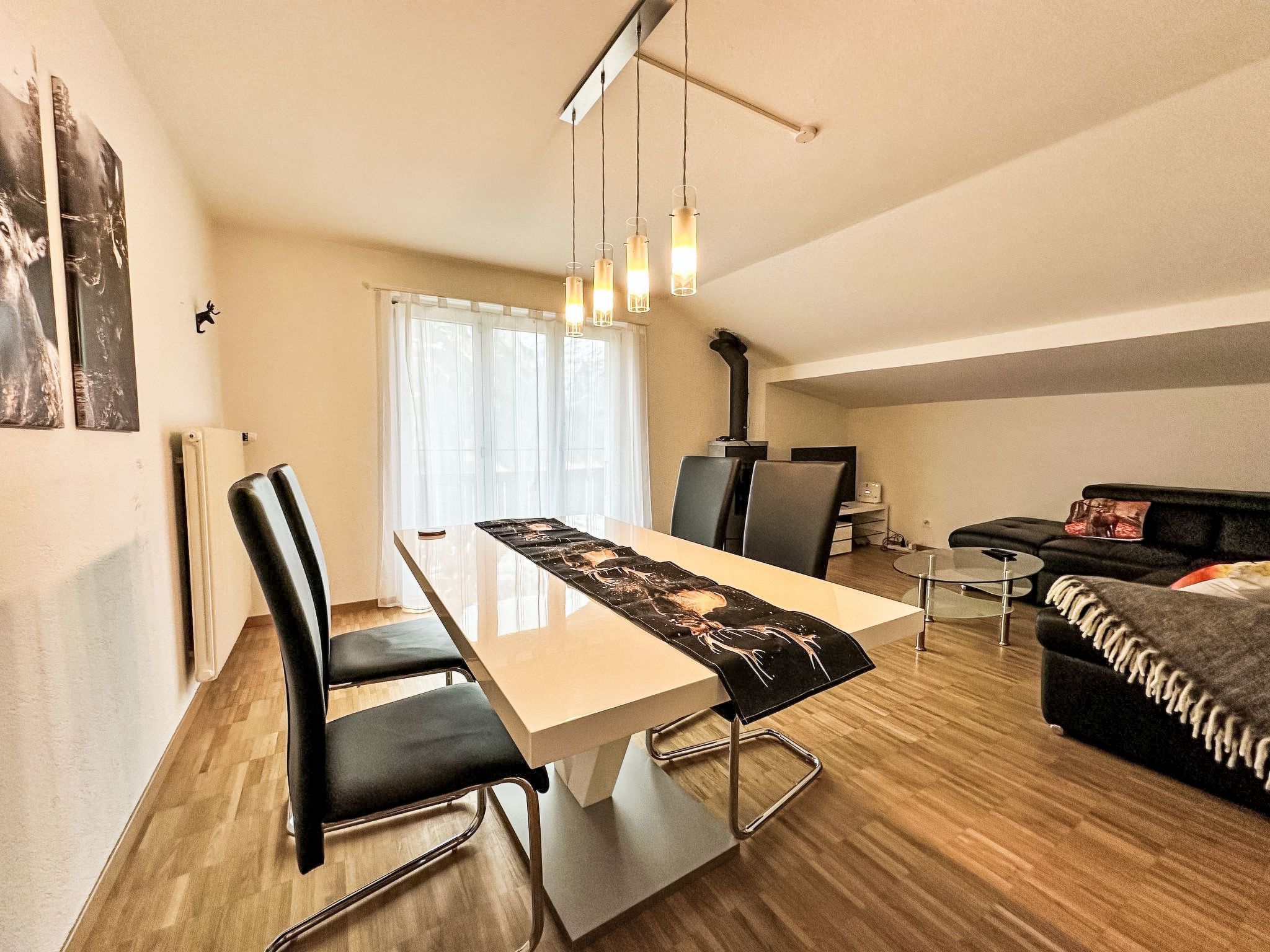 A modern living space with a dining table, chairs, a sofa, and a fireplace.