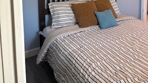 Ein Bett mit gestreifter Bettwäsche, einem hölzernen Kopfteil und einem Wandbild.