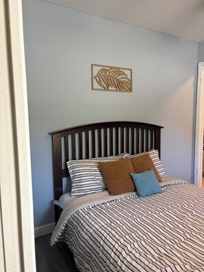 Un letto con biancheria a righe, una testata in legno e un elemento decorativo a parete.