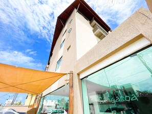 A building with a large glass facade, a visible sign reading 'Tamarindo,' and a clear sky with clouds. - Tangaroa #106 - Comfortable Apartment by Carpediem (Ipojuca)