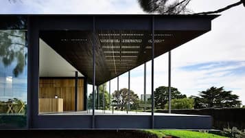A modern building with a large glass facade, a wooden interior, and a metal roof structure.