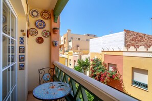 A balcony with a tiled table, decorative plates, and a view of neighboring buildings. - Apartment in Nerja Near Torrecilla Beach (Nerja)