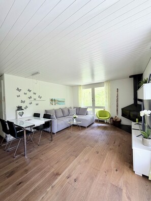 Una sala de estar moderna con un sofá modular, una mesa de comedor con sillas, un televisor y una chimenea.