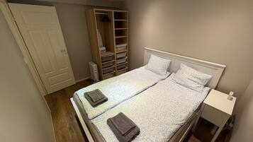 Ein Schlafzimmer mit Bett, Nachttisch, Kleiderschrank und Heizkörper.