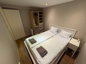 Ein Schlafzimmer mit Bett, Nachttisch, Kleiderschrank und Heizkörper.