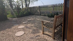 Eine hölzerne Bank und ein Steinweg, der zu einer Holztür führt.