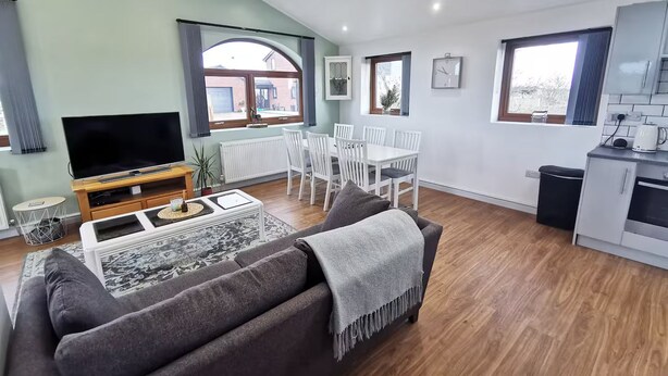 Ein moderner Wohnbereich mit Sofa, Fernseher, Esstisch und Küchenzeile.