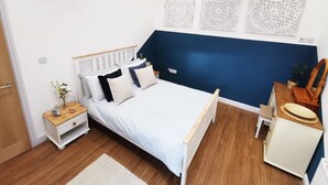 Ein Schlafzimmer mit einem Bett, Nachttischen, einer Kommode und Wanddekoration.