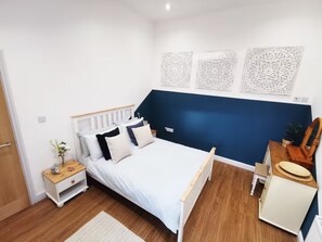 Ein Schlafzimmer mit einem Bett, Nachttischen, einer Kommode und Wanddekoration.