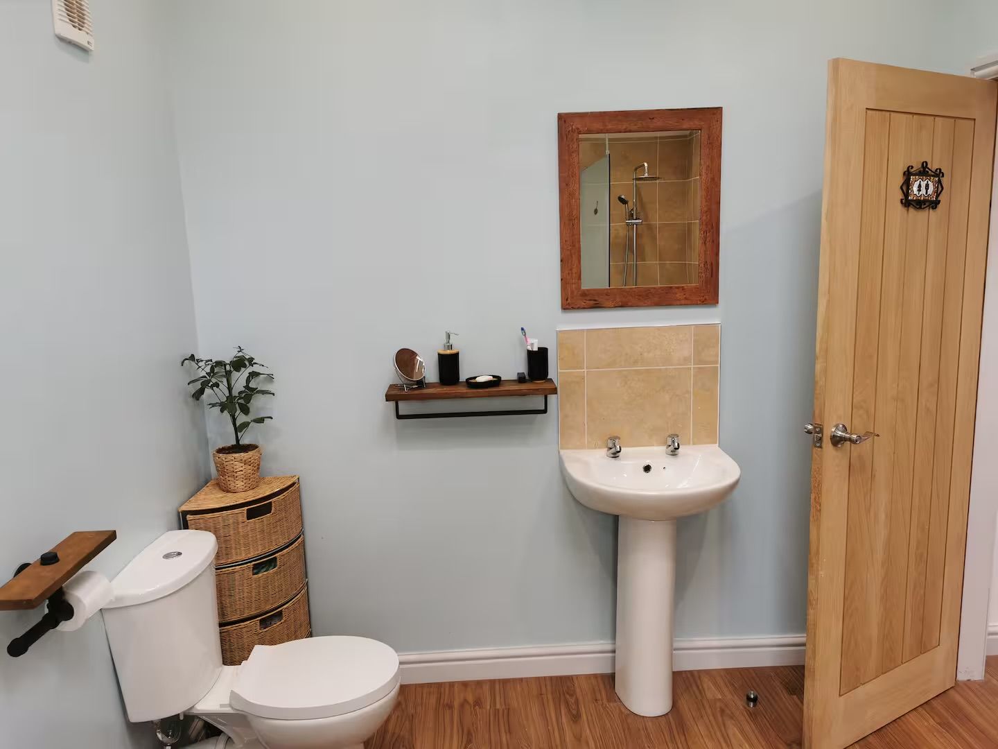 Un baño con inodoro, lavamanos y puerta de madera.