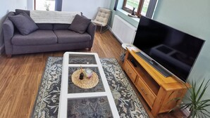 Ein Wohnzimmer mit einer Couch, einem Couchtisch, einem Fernseher und einem Fenster mit Blick.