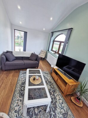 Ein Wohnzimmer mit einer Couch, einem Couchtisch, einem Fernseher und einem Fenster mit Blick.