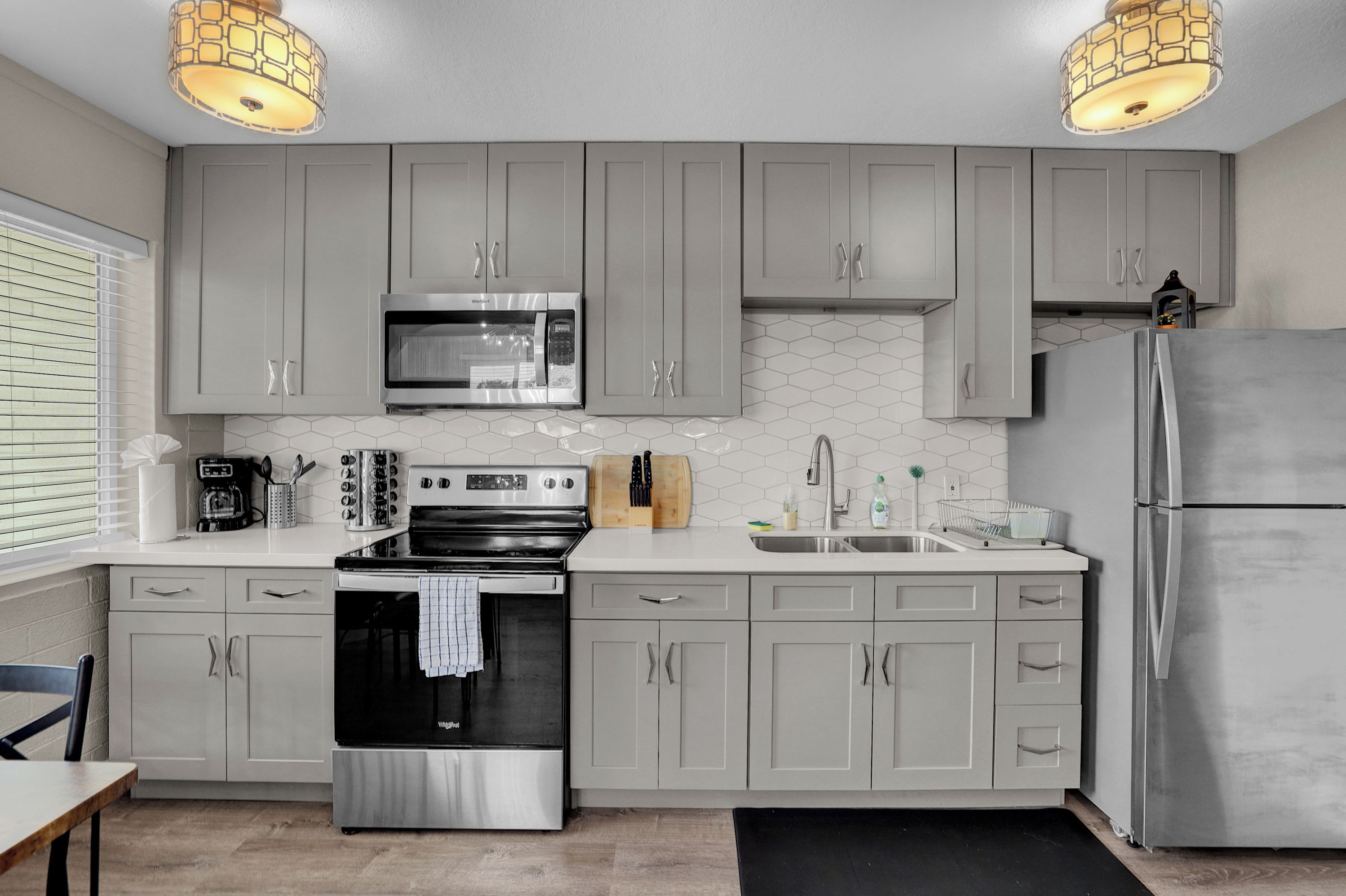 A modern kitchen with grey cabinets, stainless steel appliances, and a black countertop.