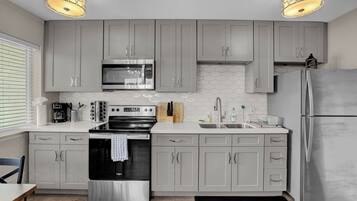 A modern kitchen with grey cabinets, stainless steel appliances, and a black countertop.