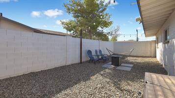 A backyard with a white brick wall, a tree, and a hammock.