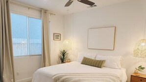 A bedroom with a large bed, bedside lamps, a window with curtains, and a ceiling fan. - Cozy King Bed Suite | Near Shopping & DT Visalia (Visalia)