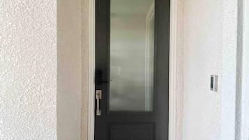 A narrow hallway leading to a dark door with a frosted glass panel.