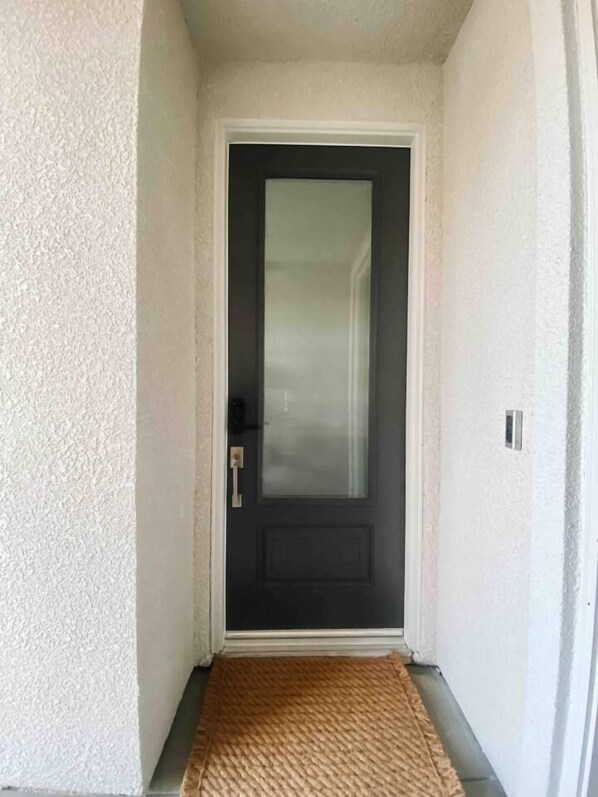 A narrow hallway leading to a dark door with a frosted glass panel.