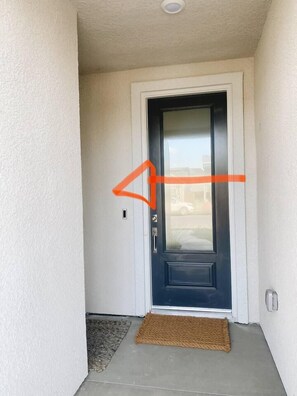 A door with a doormat, a small step, and a wall-mounted light fixture.
