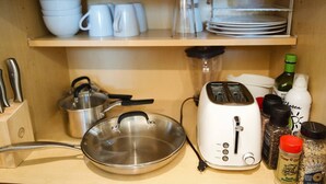 A kitchen with a toaster, a pan, and various kitchen utensils on the counter. - Cozy King Bed Suite | Near Shopping & DT Visalia (Visalia)