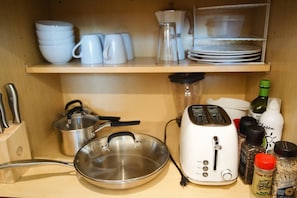Keittiössä on leivänpaahdin, paistinpannu ja erilaisia keittiövälineitä työtasolla.