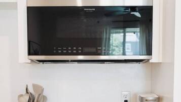 Une cuisine équipée d’un four à micro-ondes encastré, d’une bouilloire et d’une casserole sur une plaque de cuisson à induction.