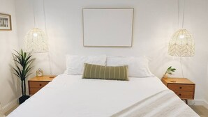 A neatly made bed with white linens, two bedside tables with lamps, and a framed picture on the wall. - Cozy King Bed Suite | Near Shopping & DT Visalia (Visalia)