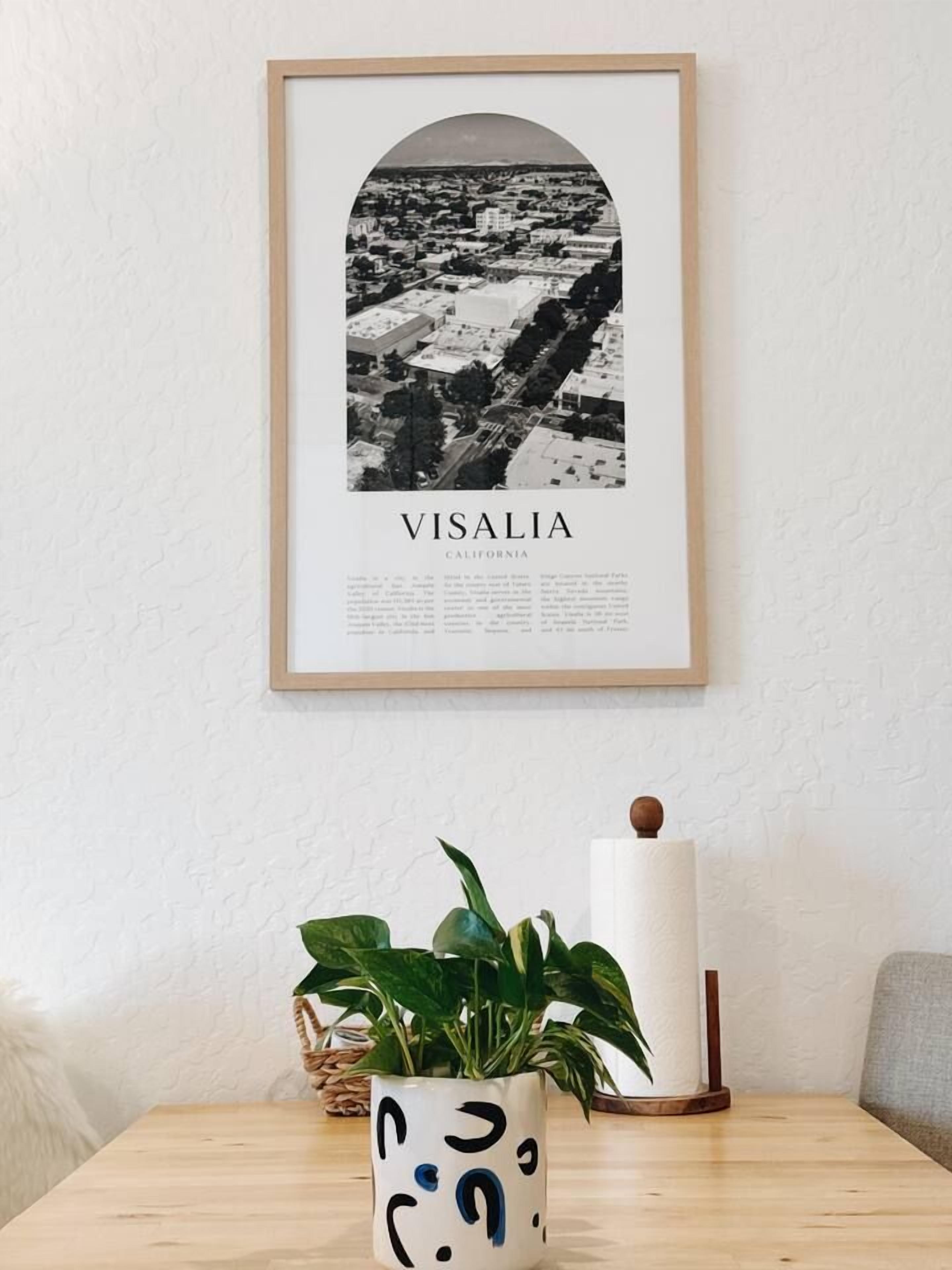 Eine gerahmte, schwarz-weiß Karte von Visalia, Kalifornien, mit einem Holztisch darunter, auf dem sich ein Blumentopf und eine Kerze befinden.