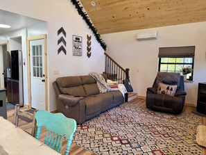 A living room with a brown sofa, a patterned rug, a teal chair, and a fireplace. - Adorable 2-bedroom cabin with filter lake views in charming Cascade (Cascade)