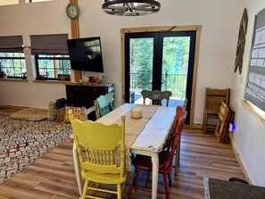 A dining area with a table, chairs, a television, and a view of the outdoors. - Adorable 2-bedroom cabin with filter lake views in charming Cascade (Cascade)
