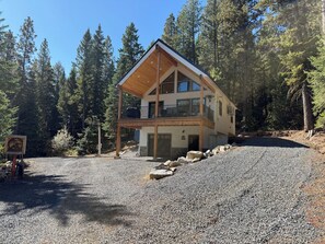 A two-story cabin with a balcony, surrounded by a forest. - Adorable 2-bedroom cabin with filter lake views in charming Cascade (Cascade)