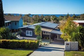 A residential property with a paved driveway, a mailbox, and a view of the sea. - Sunbound charming three-bedroom beach house (Pambula Beach)